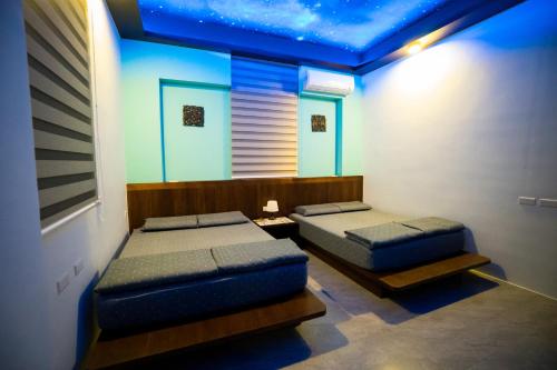 Duas camas num quarto com tecto azul em Ryan's Guesthouse em Xiyu
