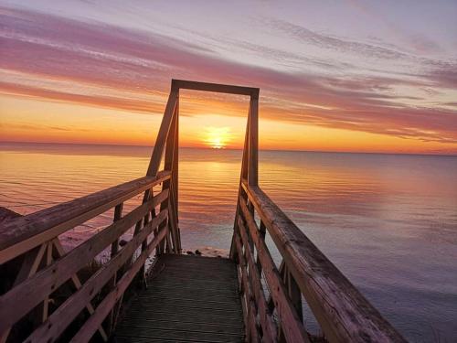 a wooden bridge leading to the ocean at sunset at Sunset House in Ulmale