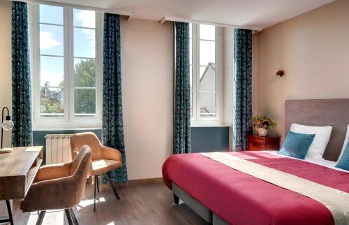 a bedroom with a bed and a desk and windows at Hôtel de France in Montmarault