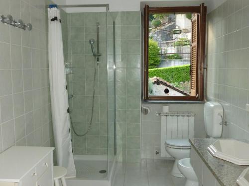 a bathroom with a shower and a toilet and a window at Hortus Lake Orta in Omegna