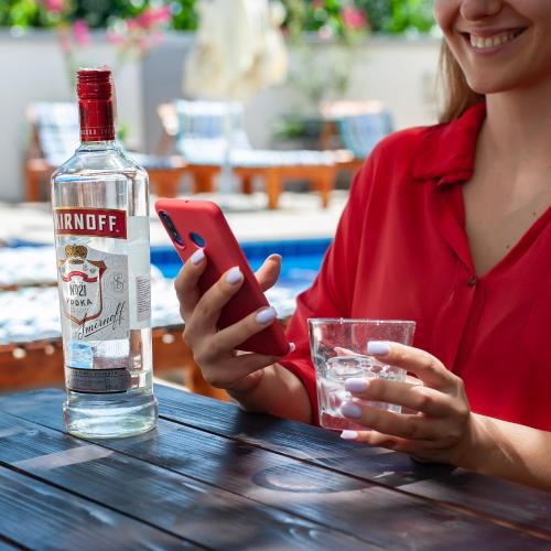 a woman sitting at a table with a bottle of whiskey and a glass at Villa Boho Cherga in Belgrade