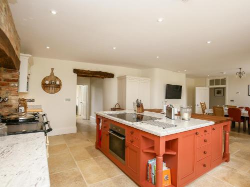 a kitchen with an orange island in the middle at Shifford Manor Farm in Witney