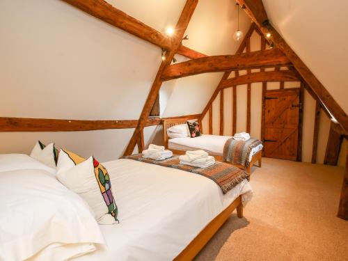 two beds in a attic room with wooden beams at Shifford Manor Farm in Witney
