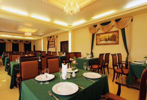 a restaurant with green tables and chairs and a chandelier at Voronezh Hotel in Voronezh