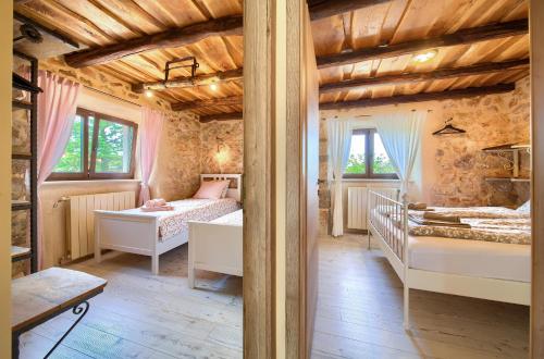 a bedroom with two beds in a room with wooden ceilings at Holiday House Ursa in Krk