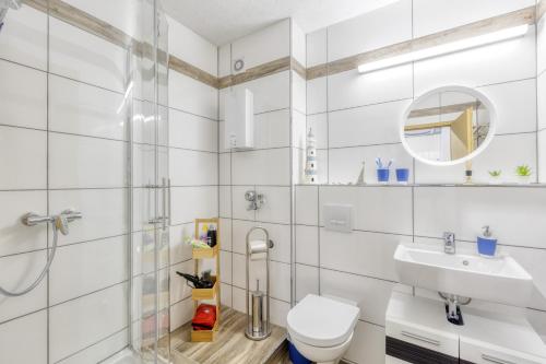 La salle de bains blanche est pourvue de toilettes et d'un lavabo. dans l'établissement Relax-Apartment mit Indoor-Pool, Fitness und Netflix am Bodensee, à Uhldingen-Mühlhofen