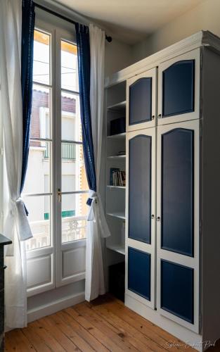 a white cabinet with blue doors in a room with a window at I love Bergerac in Bergerac