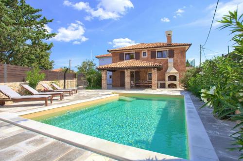 a swimming pool in front of a house at Holiday House Ursa in Krk