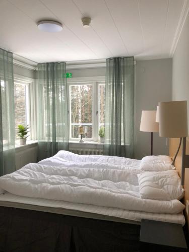 a bedroom with a large white bed with a window at Vandrarhemmet Hörneborg in Örnsköldsvik