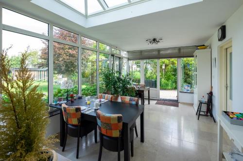 a conservatory with a dining room with a table and chairs at B&B Landleven in Hellevoetsluis