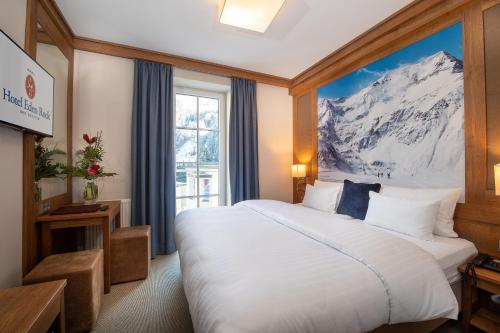 ein Hotelzimmer mit einem großen Bett mit einem Wandbild der Berge in der Unterkunft Hotel Eden Rock in Bad Gastein