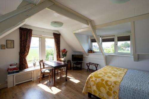 een slaapkamer met een bed, een bureau en ramen bij B&B Landleven in Hellevoetsluis