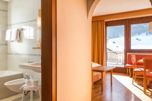 a bathroom with a tub and a sink and a table at Appartement Strobl in Sesto
