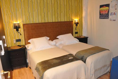 two beds in a hotel room with green wallpaper at Pensión Boutique Caravan Cinema in Bilbao
