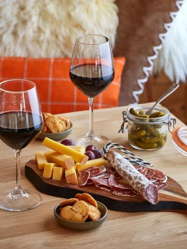a table with two glasses of red wine and cheese at Hôtel L'Arboisie in Megève