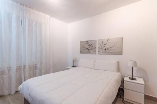 a white bedroom with a large white bed and a window at Beautiful 4pax apartment in Malasaña in Madrid