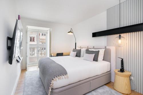 a white bedroom with a large bed and a tv at WHome | Prime Location Luxury Apartment in Lisbon