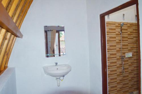 a bathroom with a sink and a mirror on a wall at Lempeh Jungle Cottage in Nusa Penida