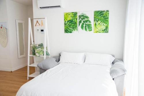 a white bedroom with a white bed and plants on the wall at L1 Apartamento O Grove Centro, Aire acondicionado, parking in O Grove