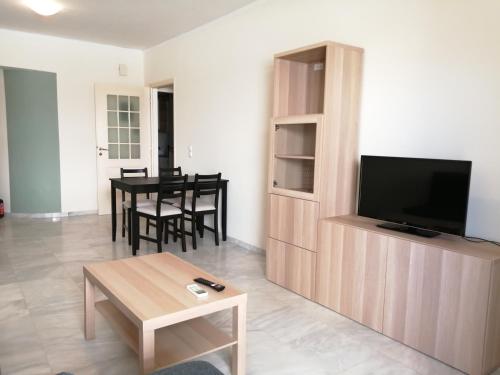 ein Wohnzimmer mit einem TV und einem Tisch in der Unterkunft Spacious Apartment in Nafplio City Center in Nafplio