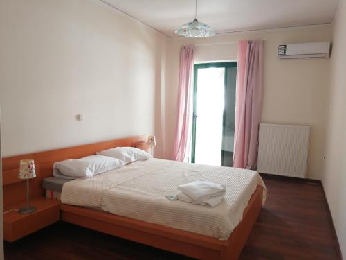 um quarto com uma cama com lençóis brancos e uma janela em Spacious Apartment in Nafplio City Center em Nafplio