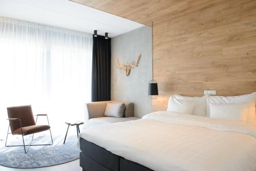 a bedroom with a large bed and a chair at Hotel de Sterrenberg - Adults Only in Otterlo