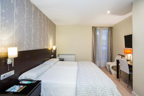 1 dormitorio con 1 cama blanca grande y escritorio en Pensión Altair, en San Sebastián