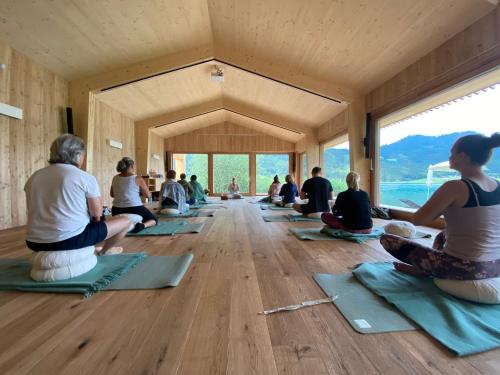 a group of people sitting in a room doing yoga at Hotel Neusacherhof in Weissensee