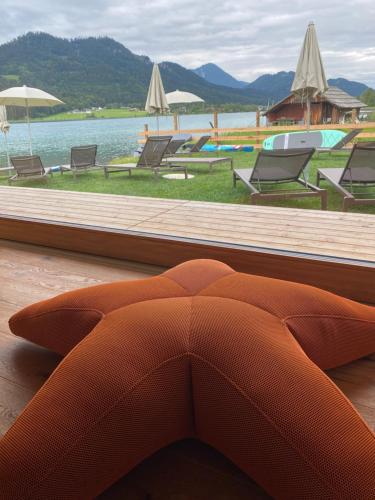 an orange couch sitting on a wooden floor next to a pool at Hotel Neusacherhof in Weissensee