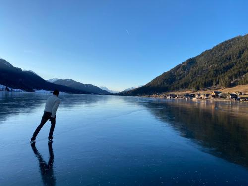 a man standing in the water on a river at Hotel Neusacherhof in Weissensee