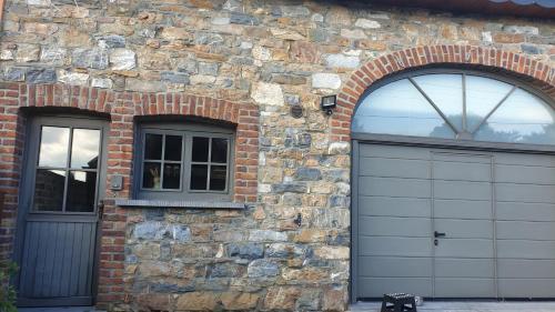 a brick building with two garage doors and two windows at Le basecamp des sommets in Stavelot