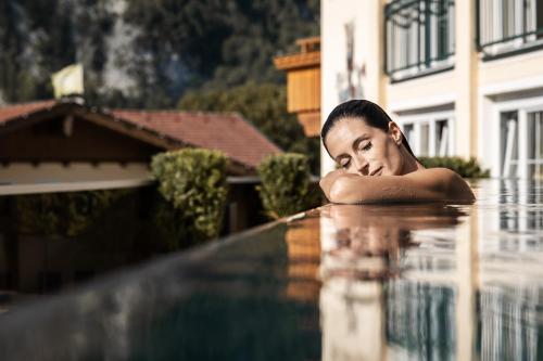 a woman laying on the edge of a swimming pool at Vier Jahreszeiten Wellnessresort Achensee in Maurach