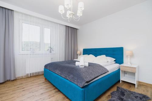 Cama azul en habitación blanca con ventana en DreamView Premium Apartment Wisła Kamienna by Renters, en Wisła