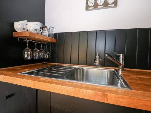 uma cozinha com um lavatório de aço inoxidável e paredes pretas em Kub House em Tring