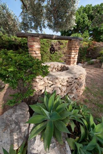 a stone fire pit in a garden with a plant at Miramare Residence in Favignana
