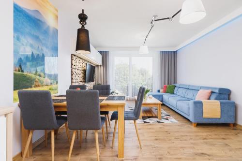 a living room with a dining table and a blue couch at DreamView Premium Apartment Wisła Kamienna by Renters in Wisła