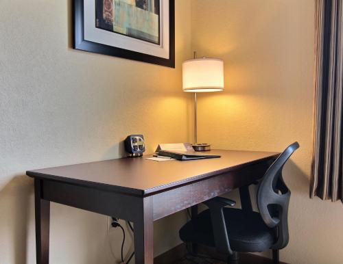 a desk in a hotel room with a lamp and a chair at Cobblestone Inn & Suites - Linton in Linton