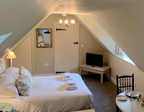 a attic room with a bed and a television at Fox Inn in Darsham