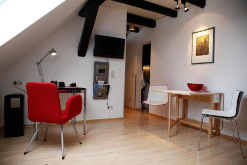 a living room with a red chair and a table at Suite „Hannover“ - modernes Apartment in Fachwerkhaus in Hannover