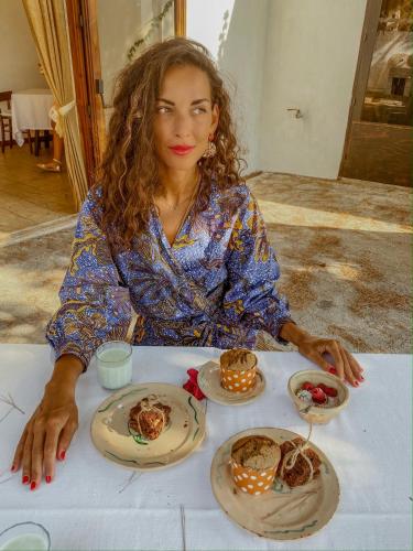 Eine Frau, die an einem Tisch mit Teller Essen sitzt. in der Unterkunft Masseria Spina Resort in Monopoli