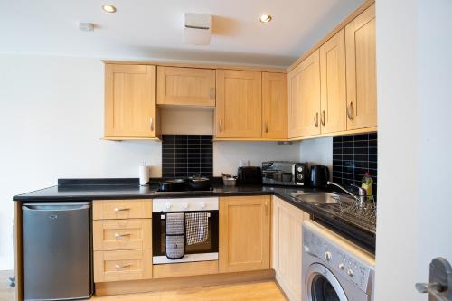 a kitchen with wooden cabinets and a dishwasher at 1-bedroom apartment with balcony, Hoddesdon in Hoddesdon