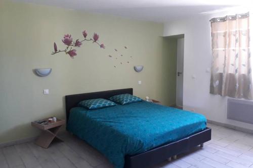 um quarto com uma cama com lençóis azuis e flores na parede em Au Dom-icile em Monceaux-en-Bessin