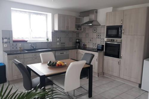 une cuisine avec une table avec un bol de fruits dessus dans l'établissement Au Dom-icile, à Monceaux-en-Bessin