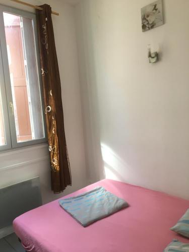 Cama rosa en habitación con ventana en Providence, en Carcassonne