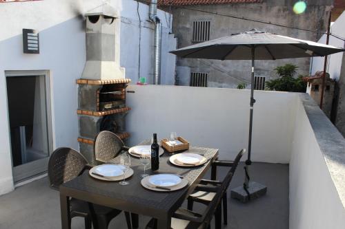 una mesa negra con sillas y una sombrilla en el patio en A Casa da Avó Cuca en Amiães de Baixo
