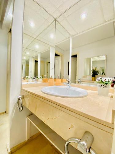 a bathroom with a sink and a large mirror at Portico Sevilla in Seville