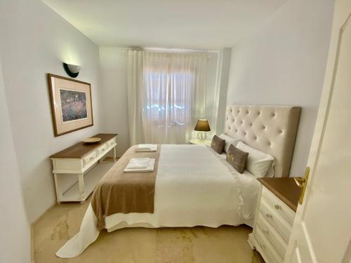 a white bedroom with a large bed and a desk at Portico Sevilla in Seville