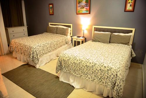 a bedroom with two beds and a table with a lamp at Batey Hotel Boutique in Boca Chica