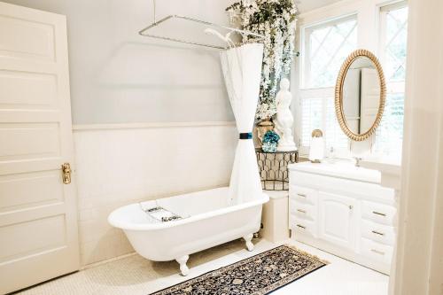 a bathroom with a tub and a sink and a mirror at Heritage House Bed & Breakfast - Boutique Adults-Only Inn in Opelika