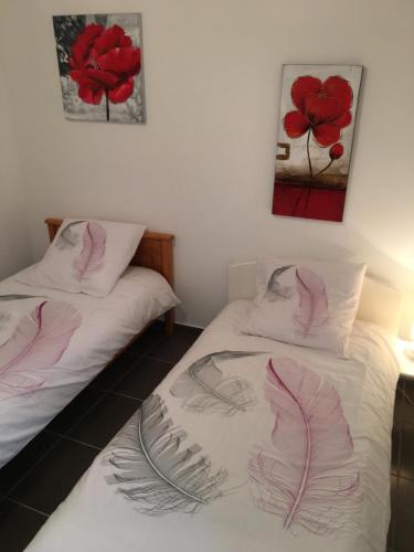 ラ・トゥール・デュ・パンにあるAppartement la Gareの壁に絵が飾られた部屋にベッドが2つある